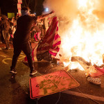 5月31日、ワシントンで、米国旗などを燃やす抗議デモの参加者(AFP時事)
