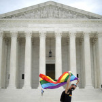 １５日、ワシントンの米連邦最高裁前で、ＬＧＢＴ（性的少数者）権利拡大運動の象徴である虹色の旗を掲げる市民（ＡＦＰ時事）
