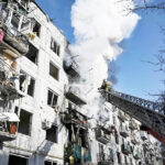 ２４日、爆撃を受けたウクライナ東部の町で、建物の放水作業に当たる消防隊（ＡＦＰ時事）