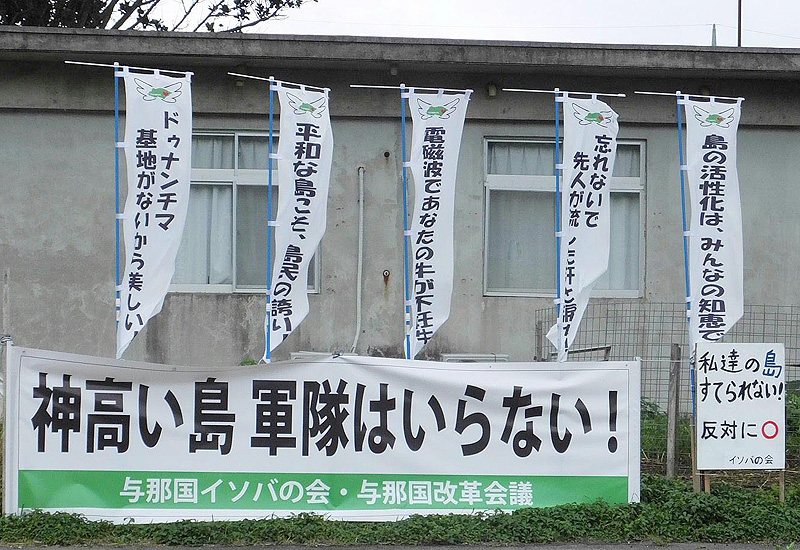 自衛隊配備反対派が多く移り住んでいる比川地区にあった横断幕と「電磁波であなたの牛が不妊牛」などと書かれた旗 与那国町住民投票紀行記 「反対派は外から来る」